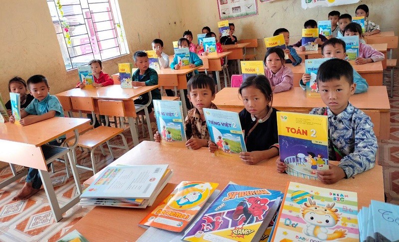 Học sinh Trường PTDTBT Tiểu học xã Ngọc Long (Yên Minh, Hà Giang) cầm trên tay những cuốn sách giáo khoa do các trường học tại Hà Nội trao tặng. Ảnh: NTCC