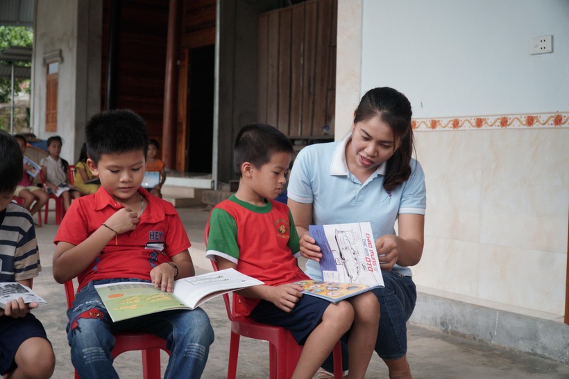 Cô giáo hướng dẫn trẻ đọc sách tại nhà.