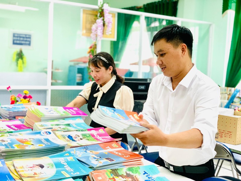 Giáo viên Trường Phổ thông Dân tộc Bán trú Tiểu học & THCS Đinh Thanh Kháng bao bọc sách giáo khoa trước khi cho học trò mượn sử dụng trong năm học. Đây là cách làm để tăng “tuổi thọ” cho sách, có thể tái sử dụng nhiều năm.