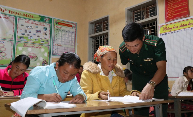 Thầy giáo Vì Văn Liêm, Đồn biên phòng Mường Lạn đang chỉ dẫn người dân đọc và viết chữ.