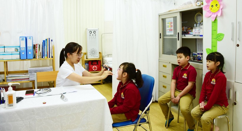 Cô Trần Thanh Thủy, nhân viên y tế Trường Tiểu học Lý Thái Tổ (Hà Nội) thực hiện công tác khám bệnh cho học sinh. Ảnh: NTCC
