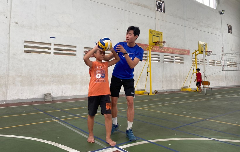 Sinh viên Lê Hoàng Long đang hướng dẫn cho một bạn nhỏ về tư thế đỡ bóng. 