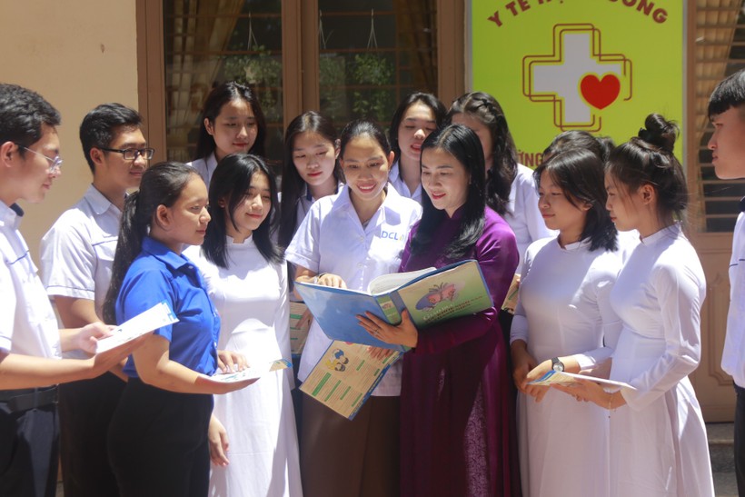 Bà Nguyễn Thị Xuân Hương (áo dài tím) cùng cán bộ y tế tư vấn cho học sinh về SKSS vị thành niên. Ảnh: Thành Tâm