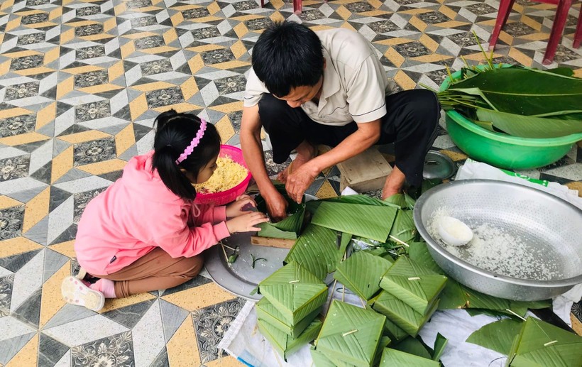 Học sinh Trường Tiểu học Phan Đăng Lưu (quận Hải Châu, TP Đà Nẵng) cùng gia đình gói bánh chưng đón Tết cổ truyền trong chuỗi hoạt động Xuân hiếu hạnh. Ảnh: NTCC
