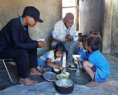 A Lương (bên trái) cùng 2 em và ông nội trong bữa cơm đạm bạc. Ảnh: Trúc Hân