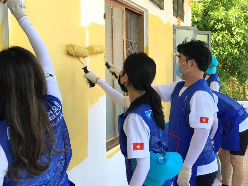 Các cán bộ ngân hàng IBK (Hàn Quốc) cùng các thầy cô giáo và các em học sinh trường Tiểu học và THCS Phú Cường tham gia sơn lại trường, lớp học