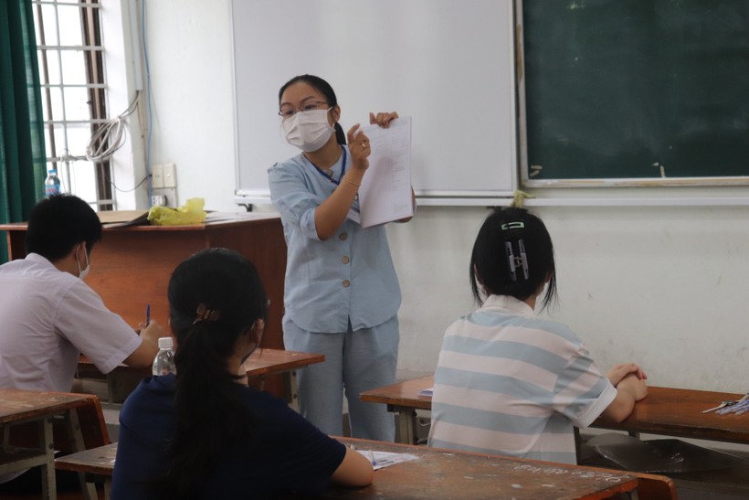 Cán bộ coi thi tại điểm thi Trường THPT Phan Châu Trinh (Đà Nẵng) hướng dẫn thí sinh ghi các thông tin cá nhân vào giấy làm bài thi. 