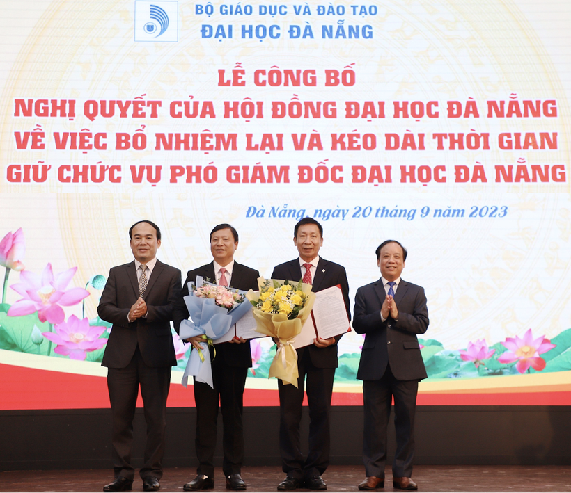 Giám đốc ĐH Đà Nẵng (bên phải) và Chủ tịch Hội đồng ĐH Đà Nẵng trao các Nghị quyết và tặng hoa chúc mừng các Phó Giám đốc. 