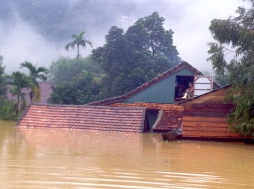Nước lũ lên cao, người dân Tân Hóa chỉ biết ngồi trên gác mái nhà. (Ảnh CTV)