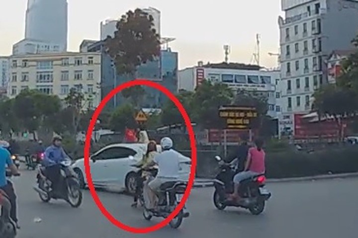 Hai bé gái ung dung ngồi nóc ôtô chạy giữa phố Hà Nội