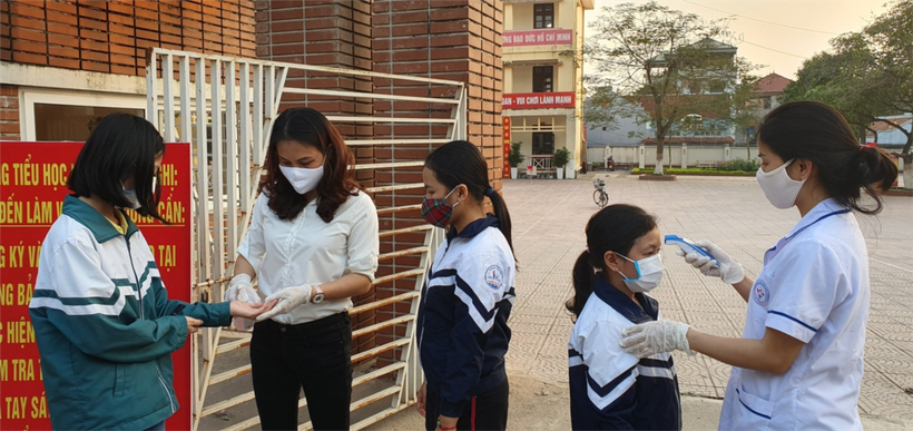 Nhân viên y tế đo thân nhiệt cho học sinh tại cổng Trường Tiểu học Liên Bảo. Ảnh tư liệu