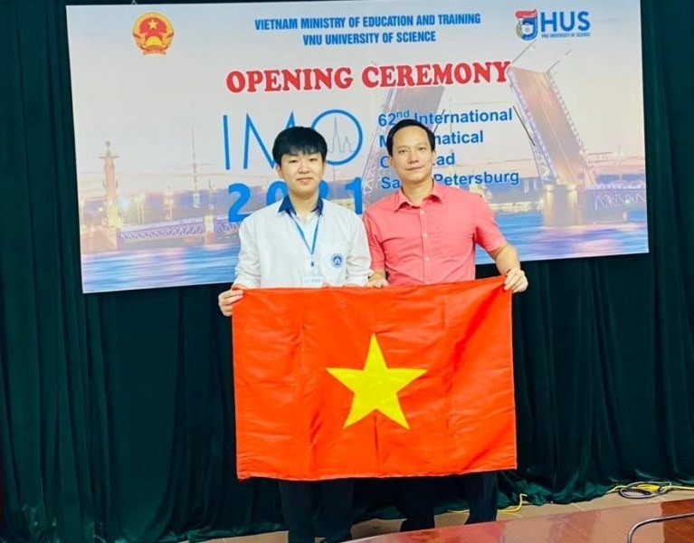 Em Vũ Ngọc Bình (bìa trái) cùng thầy giáo Lê Xuân Đại trong lễ khai mạc IMO 2021