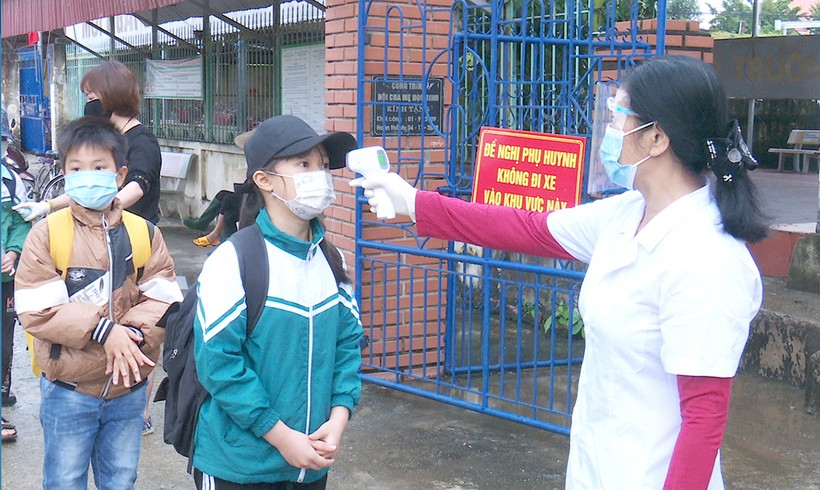 Nhân viên y tế trường Tiểu học Bản Nguyên 2 (huyện Lâm Thao) đo thân nhiệt học sinh trước khi vào lớp. Ảnh Hồng Vân