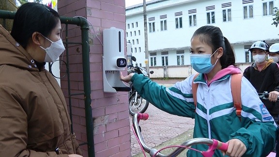 Học sinh huyện Vị Xuyên đo thân nhiệt và rửa tay khử khuẩn bằng máy tự động trước khi vào trường học. Ảnh: Thu Liễu. 