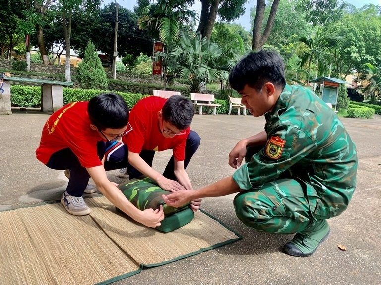 Học sinh thực hành gấp chăn, màn theo hướng dẫn của các chiến sĩ.