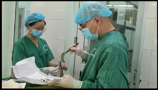 Bác sĩ thực hiện mổ cấp cứu lấy dị vật trong bụng bệnh nhân. Ảnh cắt từ clip
