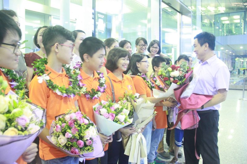 Thầy Đoàn Công Thạo - Hiệu trưởng Trường THCS Giảng Võ tặng hoa chúc mừng học sinh khi ra đón đoàn tại sân bay tối muộn ngày 7/7