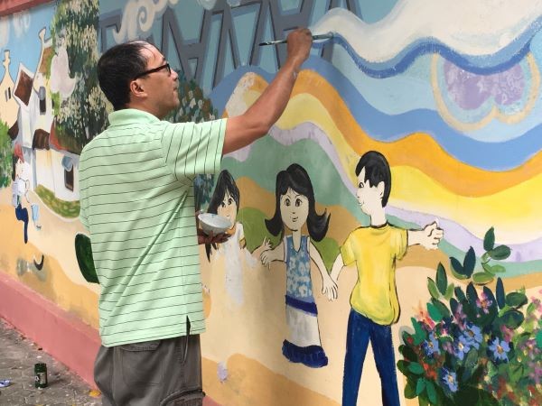Thầy Lâm Tuấn Phong là người biến những bức tường đơn điệu bao quanh trường học thành những bức tranh sinh động, sặc sỡ.