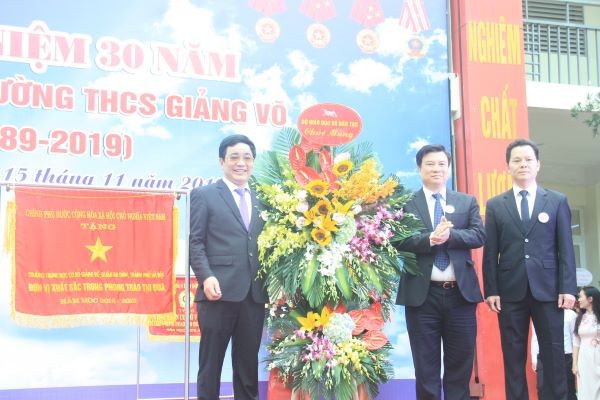 Thứ trưởng Bộ GD&ĐT Nguyễn Hữu Độ (giữa) tặng hoa chúc mừng nhà trường.