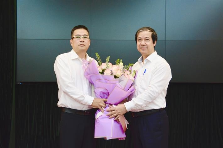 Bộ trưởng Bộ GD&ĐT Nguyễn Kim Sơn trao Quyết định và tặng hoa chúc mừng tân Phó Vụ trưởng Vụ Tổ chức cán bộ.