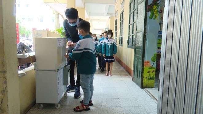 Học sinh tiểu học sử dụng máy khử khuẩn đa năng.