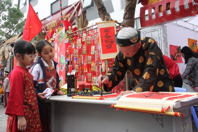Học sinh xem ông Đồ viết chữ trong lễ hội Xuân.