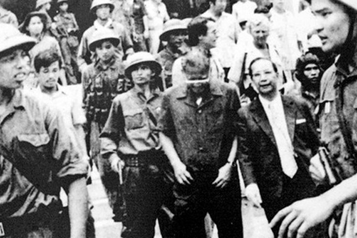 Đại úy Thệ (bìa phải) tay cầm súng ngắn, áp giải Dương Văn Minh ra Đài phát thanh để đọc lời tuyên bố đầu hàng. Ảnh: TL