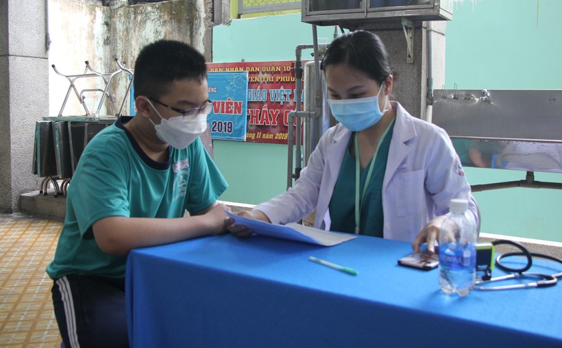Nhân viên y tế tư vấn cho học sinh TPHCM trước khi tiêm vắc xin Covid-19.