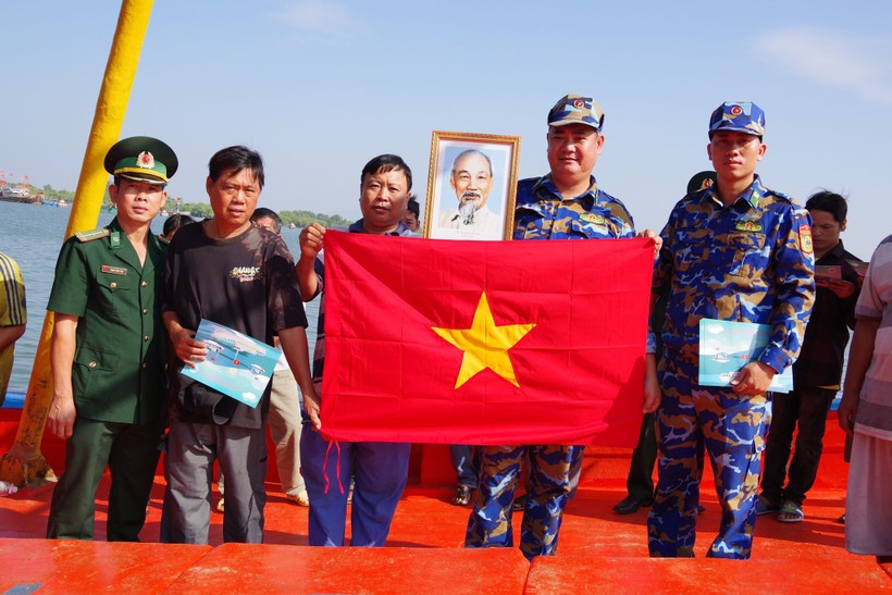 Cán bộ biên phòng tặng cờ Tổ quốc, phát tờ rơi tuyên truyền cho ngư dân.
