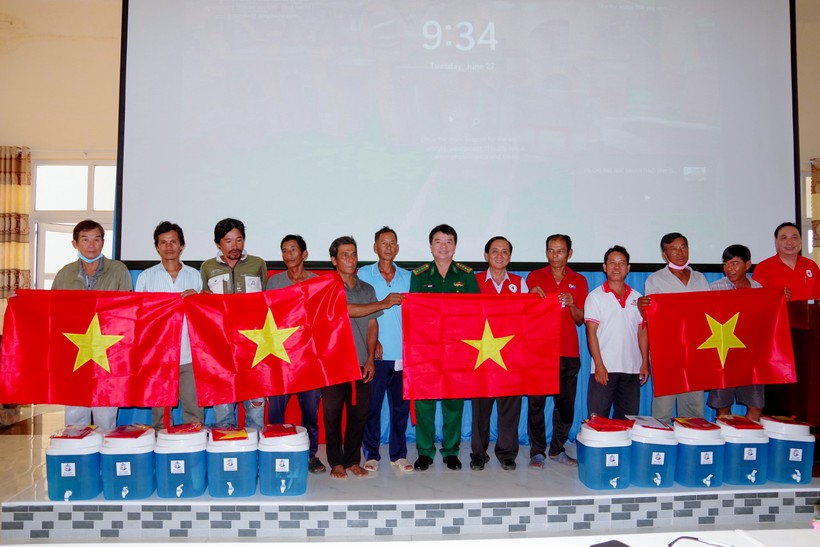 Ban tổ chức trao tặng cờ Tổ quốc và bình lọc nước cho ngư dân. (Ảnh: Hoàng Đoán)