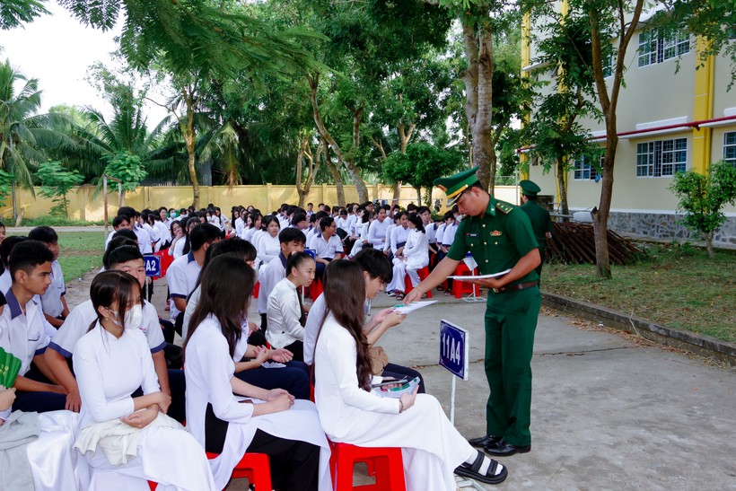 Cán bộ đồn Biên phòng Trung Bình phát tờ rơi tuyên truyền cho các em học sinh.