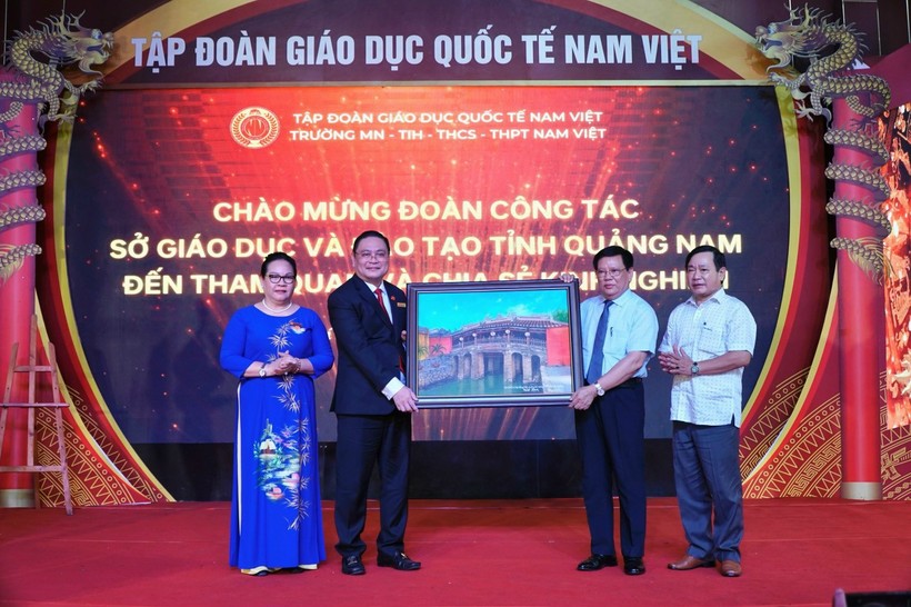 Ông Thái Viết Tường (thứ 2 từ phải qua) tặng bức tranh Chùa Cầu cho lãnh đạo Trường Trường Mầm non-TH-THCS-THPT Nam Việt.