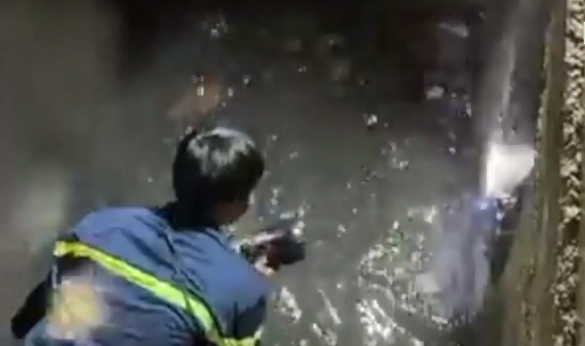 Lực lượng cứu hộ cứu nạn đã bật nắp bê tông của cống thoát nước để tìm kiếm nạn nhân. (Ảnh được cắt từ clip).