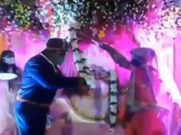 Cặp đôi người Ấn Độ dùng que tre để trao vòng hoa tín vật  nhằm giữ khoảng cách trong đám cưới.
