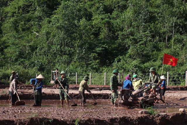 Cán bộ, chiến sĩ đồn Biên phòng CKQT Cha Lo hướng dẫn và giúp đỡ người dân xã Dân Hóa trồng lúa nước.