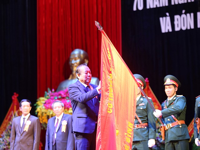 Đồng chí Trương Hoà Bình, Uỷ viên Bộ Chính trị, Phó Thủ tướng Thường trực Chính phủ gắn huân chương Độc lập hạng Nhất lên Quân kỳ.