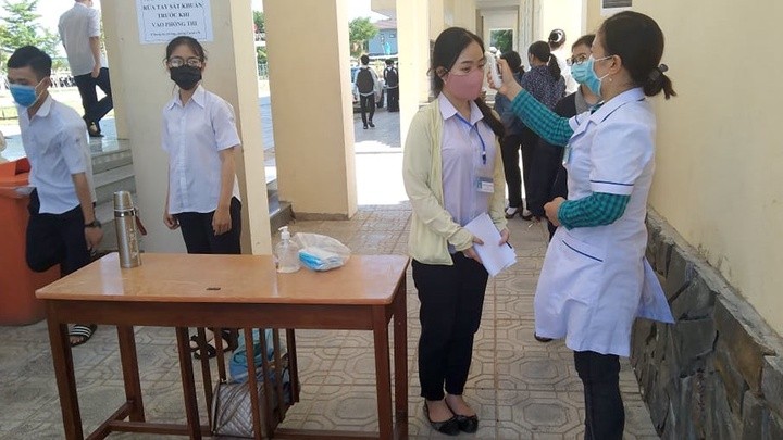 Nhân viên y tế đo thân nhiệt của học sinh khi đến trường học