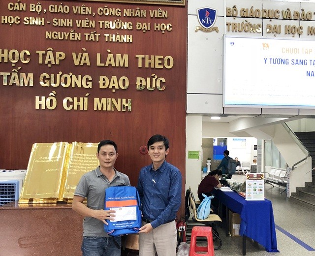 Thạc sĩ Nguyễn Bá Anh (bên phải) trao biểu trưng ba lô và học bổng cho đại diện của Báo Giáo dục & Thời đại