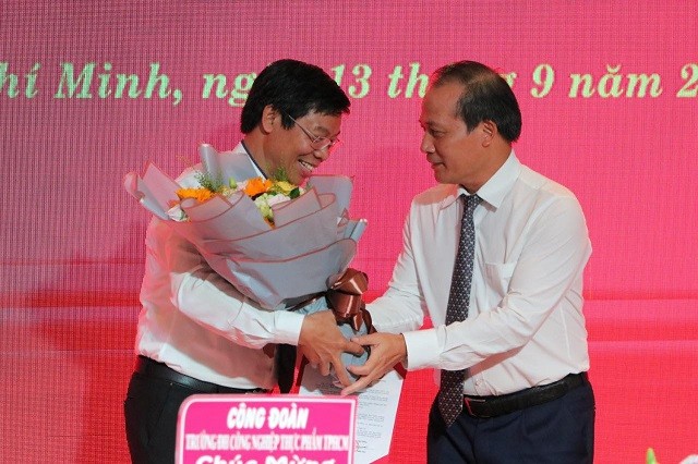 TS. Cao Quốc Hưng – Ủy viên Ban Cán sự Đảng, Thứ trưởng Bộ Công Thương (bên phải) trao quyết định bổ nhiệm và hoa chúc mừng cho tân hiệu trưởng HUFI