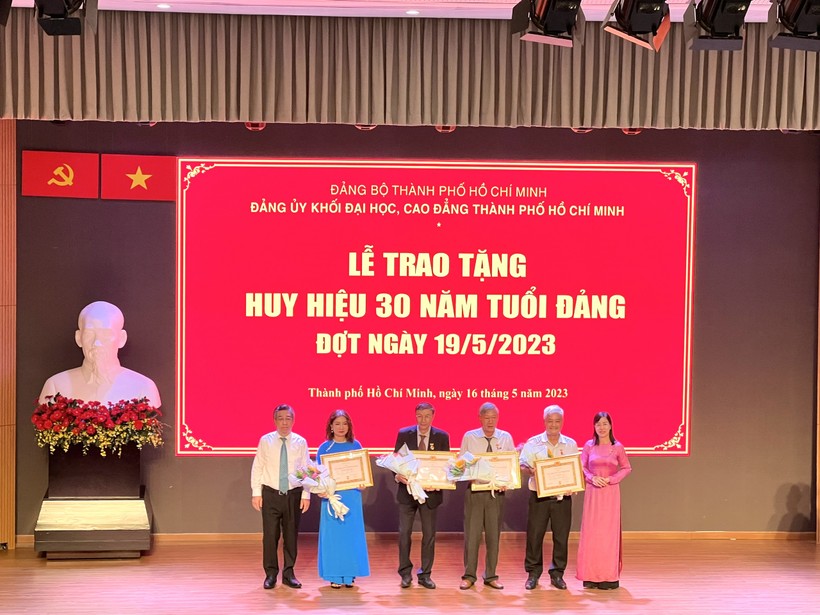 Bà Nguyễn Thị Là, Phó Bí thư Thường trực Đảng ủy Khối Đại học, Cao đẳng TPHCM (bìa phải) trao tặng Huy hiệu 30 năm tuổi Đảng cho các đảng viên. 