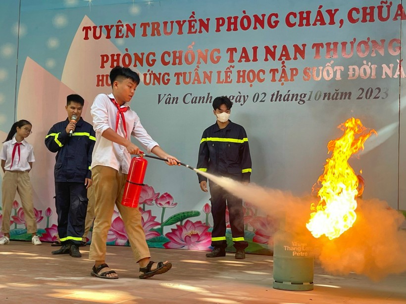 Học sinh Trường THCS Vân Canh thực hành kỹ năng sử dụng bình chữa cháy mini để dập tắt đám cháy giả định. 