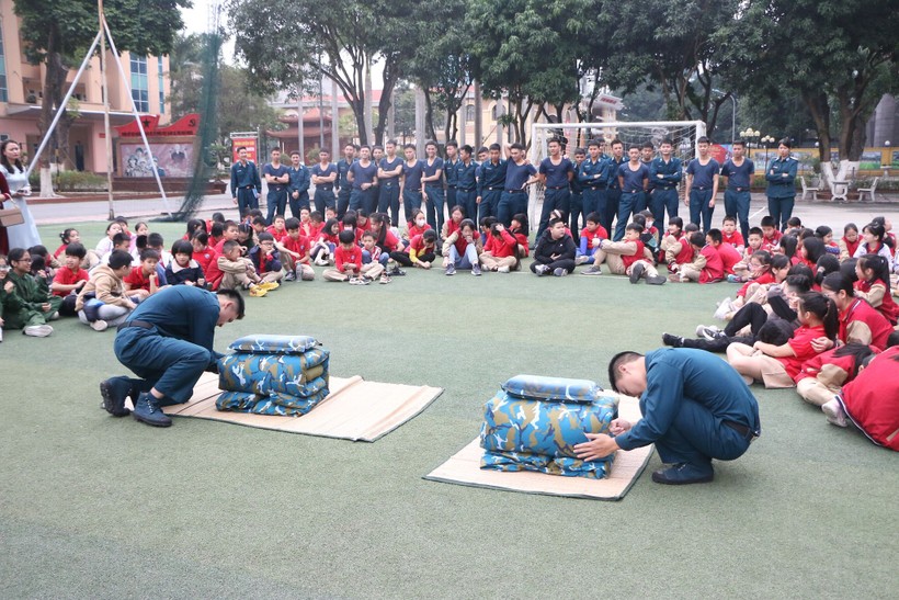 Các chiến sĩ thực hiện thao tác gấp chăn gối màn theo quy định trong quân đội để học sinh cùng theo dõi.