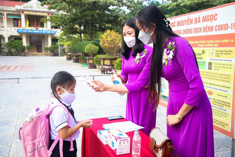 Giáo viên Trường Tiểu học Nguyễn Bá Ngọc đo thân nhiệt và sát khuẩn tay cho học sinh.