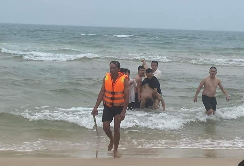 Lực lượng cứu hộ cùng người dân đưa nạn nhân vào bờ.