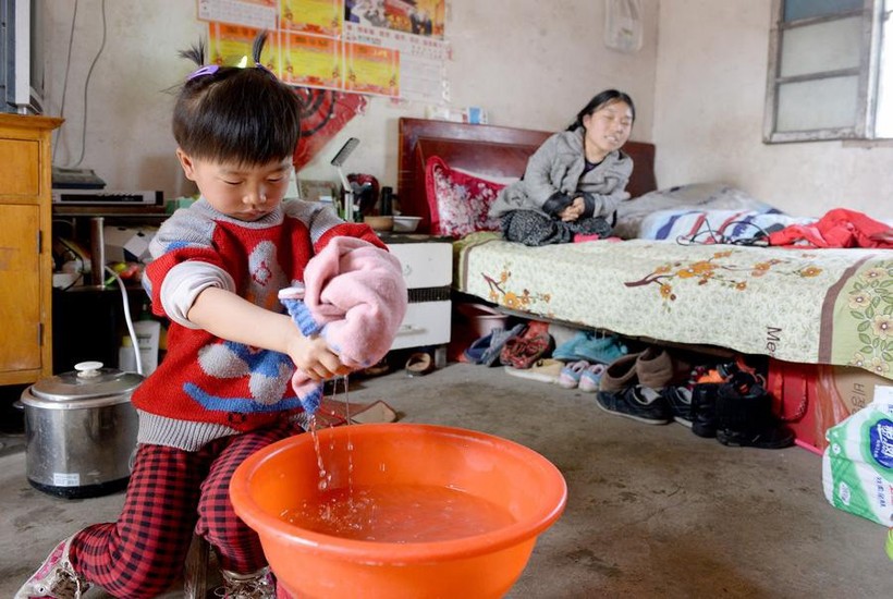 Xixi đang giặt quần áo trong nhà dưới sự hướng dẫn của mẹ.