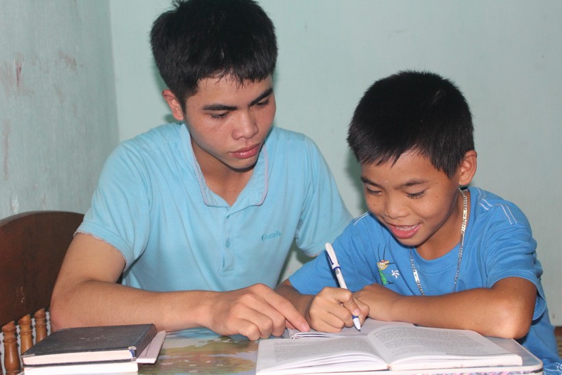 Em Lê Hữu Hiếu đang hướng dẫn em trai học bài.