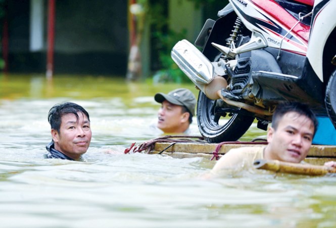 Mưa lớn kéo dài 4 ngày khiến gần 200m Quốc lộ 6 qua huyện Mai Châu, Hòa Bình bị ngập sâu gần 2m, giao thông tê liệt (trong ảnh: Người dân dùng bè chở xe máy qua đoạn ngập). Ảnh: Hiếu Lê.