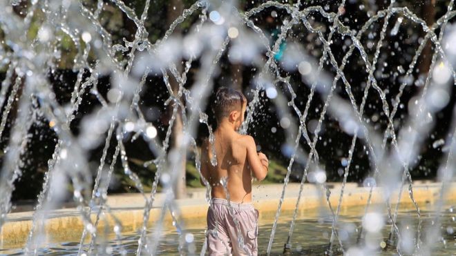 Một đứa trẻ đang tránh nóng tại một vòi nước công cộng tại	thủ đô Madrid