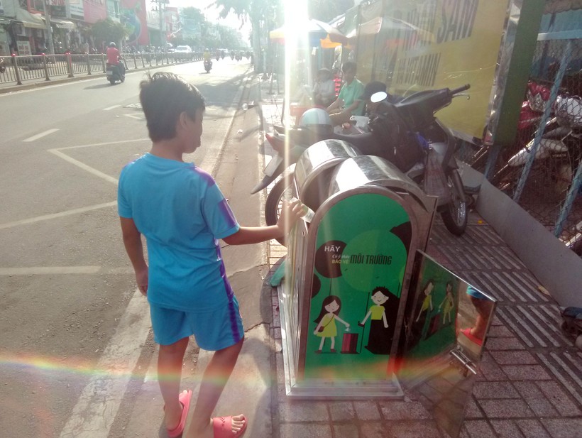Một cậu bé biết ý thức phân loại rác tại trạm xe buýt gần vòng xoay Phú Lâm, quận 6, TPHCM