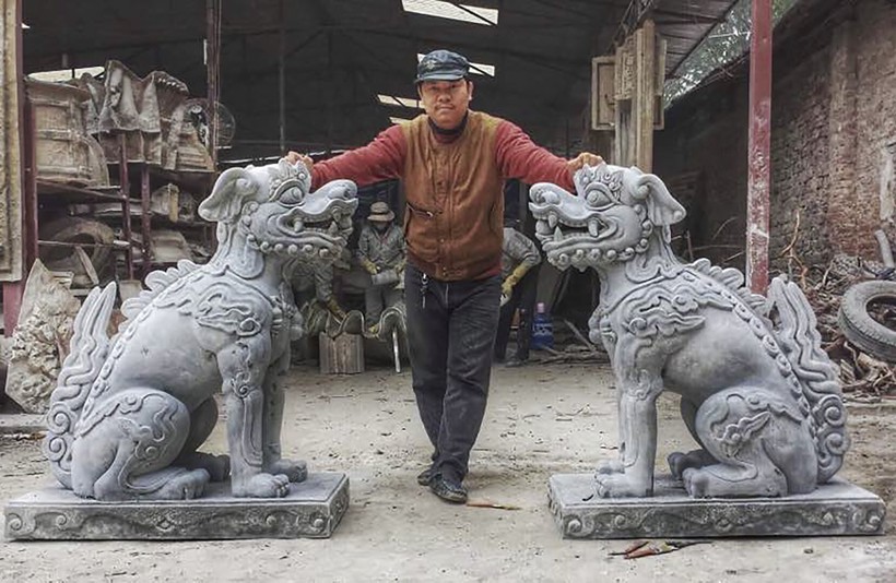 Nhà điêu khắc Nguyễn Văn Vũ bên cặp nghê do anh phục dựng